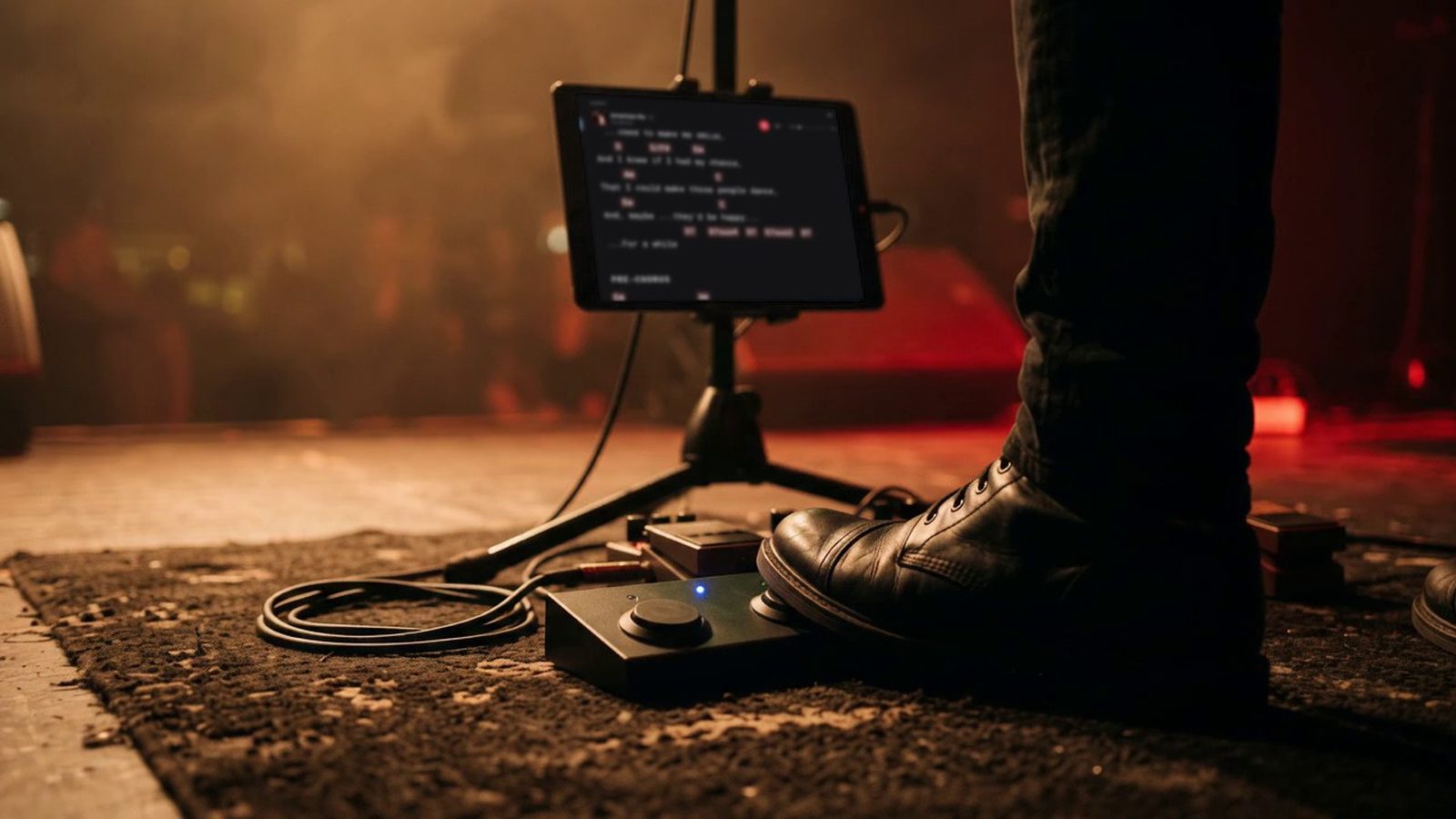 On a stage floor a boot presses a two-button Bluetooth page turner pedal, and the lyrics and chords in Stage Friend move on to the next part on a tablet on a stand.